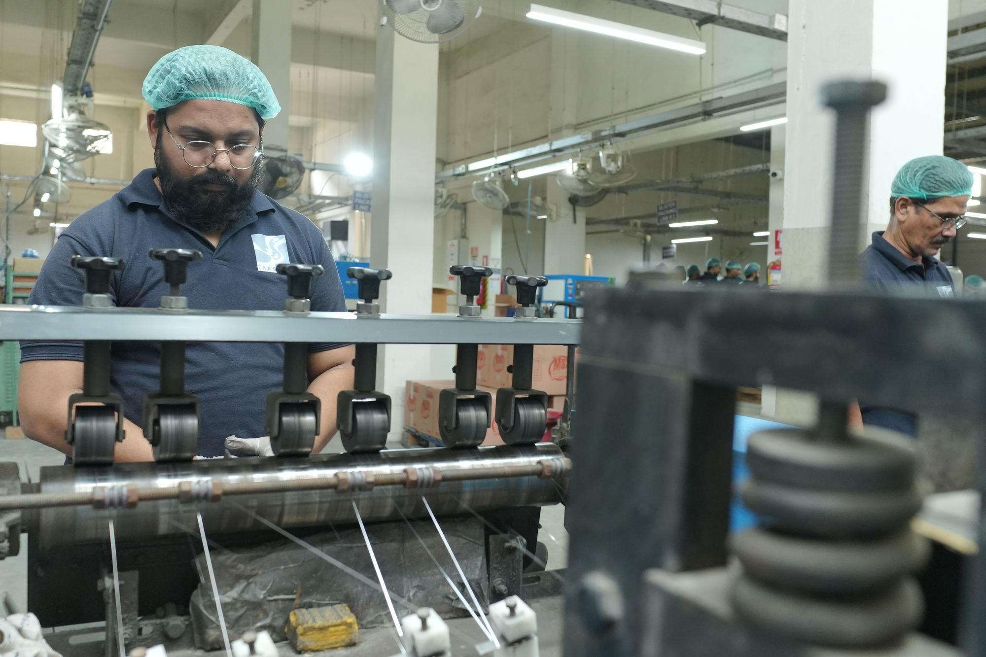 Operator running a production machine at the Korangi plant